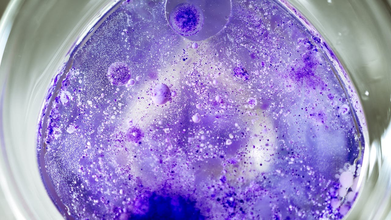 team-01 Close-up of a vibrant purple chemical reaction in a petri dish, displaying bubbles and intricate textures.