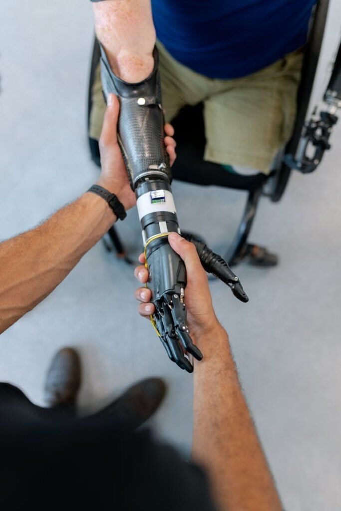 pexels photo 3912979 Close-up of a man in a wheelchair with a prosthetic hand offering a handshake.