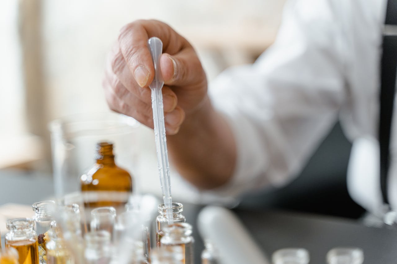 team-04 Detailed image of a person mixing essential oils in a laboratory setting.